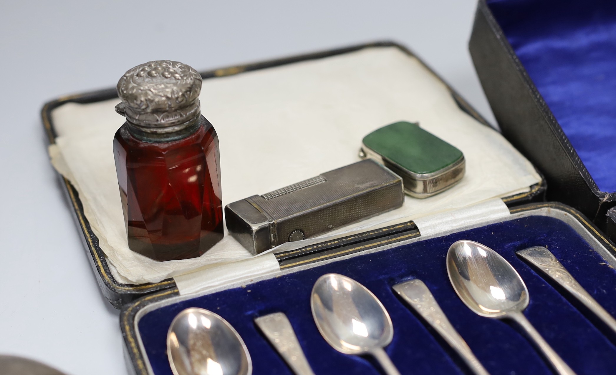 A cased set of six George V silver teaspoons, a white metal mounted glass scent bottle, a Dunhill lighter, a plated vesta, a white metal tortoise and a cased set of six plated napkin rings.